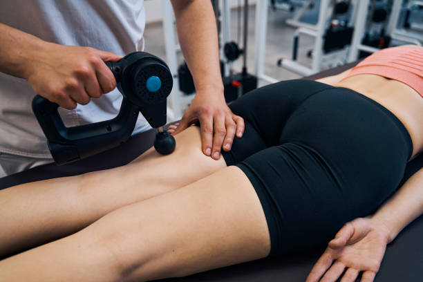 A close-up of a massage therapist performing deep tissue percussion massage on a female patient, providing remedial massage for pain relief and healing.